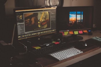 turned on two computer monitors beside two black and white keyboards on desk
