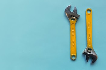 Two Adjustable Wrenches On A Blue Background
