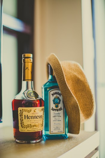 Two Assorted-brand Bottles with a Hat on One of the Bottle