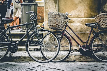 Two Black Bicycles Parting Near Wall