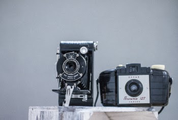Two Black Cameras on Gray Board