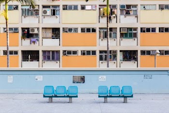 two blue 3-seat gang chairs near blue concrete wall and brown building