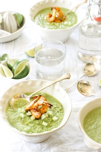two bowls filled with food on table near spoons and drinking cups