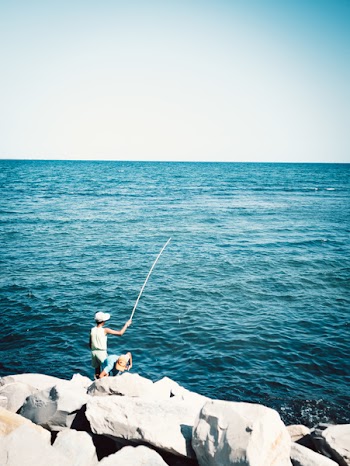 Two Boys Fishing While Standing on Boulder