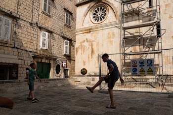 Two Boys Playing Ball Near Building