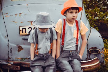 Two Boys Wearing Gray Shirts Sitting on Gray Vehicle Bumper