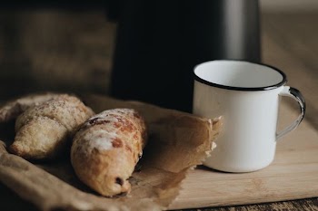 two breads on paper bag beside cup