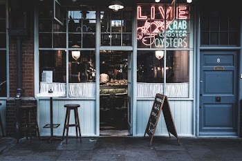 two brwon wooden empty stools outside the bar