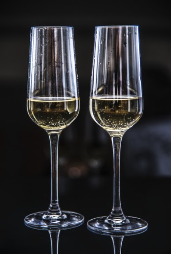 Two Clear Champagne Glasses Filled With Yellow Liquids