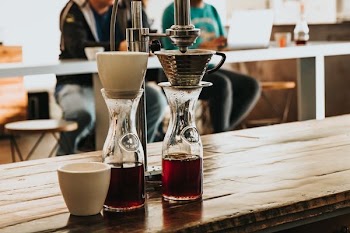 two clear glass bottles with red liquids on rbown wooden counter