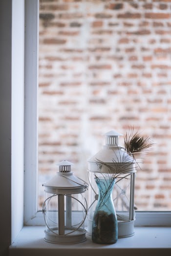 Two Clear Glass Lamp Lanterns Near Window