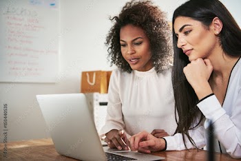 Two coworkers working on project with laptop