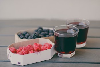 Two Drinking Glasses Filled With Raspberry and Blueberry Fruit Juices