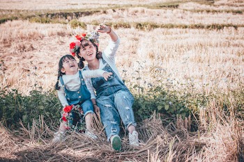 Two Girl's Looking Upward While Sitting on Brown and Green Bush