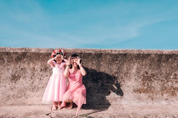 Two Girls Leaning Beside Gray Wall