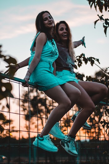 Two Girls Sitting on Gray Metal Rail