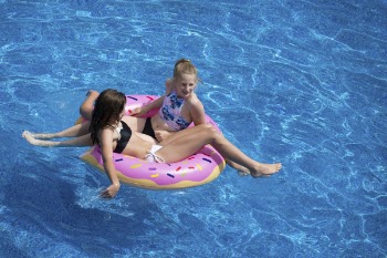 Two Girls Sitting on Pink Doughnut Pool Float