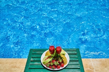 Two Glasses of Drink and Plate of Fruits by the Swimming Pool