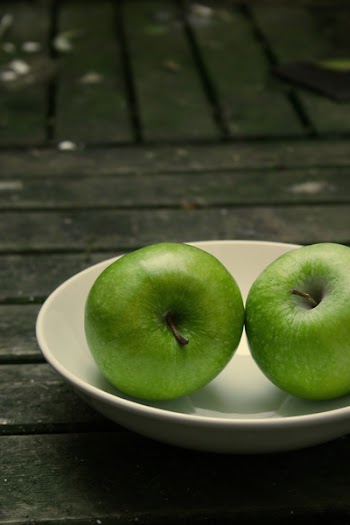 two green apples on a white plate