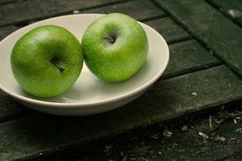 two green apples on a white plate