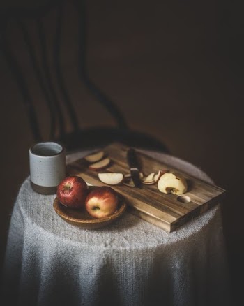 two honey crisp apples beside chopping board