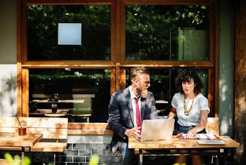 two man and woman sitting on chair in front of glass widowpane