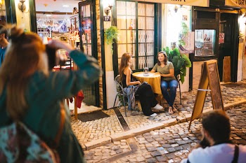 Two Man and Woman Taking Photo of Two Women Sitting and Talking Beside Round Table Beside Road With Menu Board