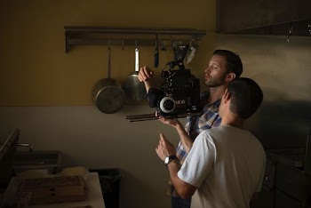 two men fixing camera inside kitchen