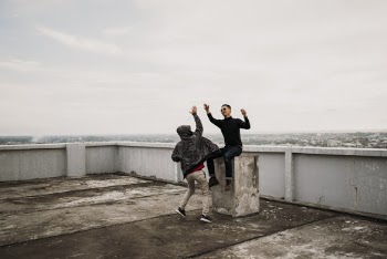 Two Men Going to High Five on Top of Building