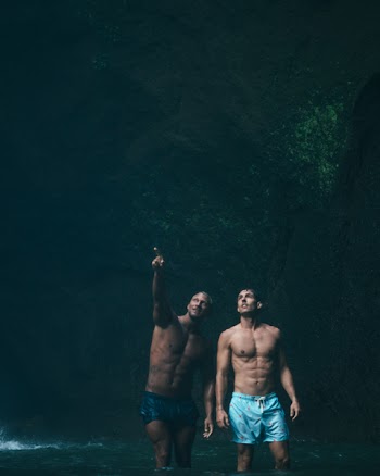 Two Men in Blue Shorts on Body of Water