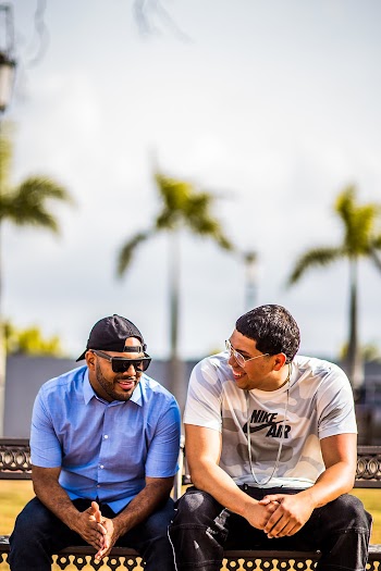 Two Men In Casual Wear Sitting Together On A Bench Talking And Smiling