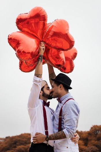 Two Men Kissing And Holding Balloons
