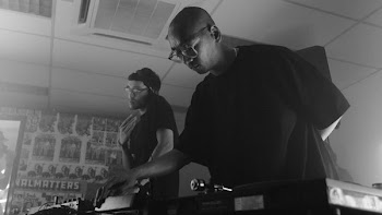two men on stage playing audio mixers
