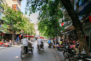 Two Men Pedaling Food Cart on Road Near Parked Motorcycles