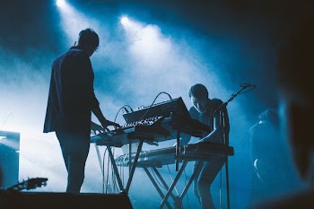 two men playing electronic keyboards on stage