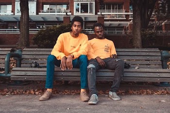 two men's sitting on brown wooden bench chair