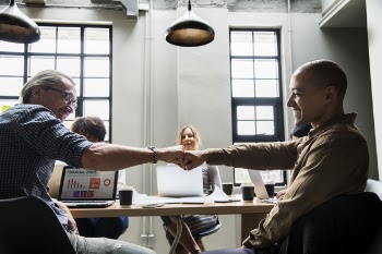 Two Men Shaking Hands While Sitting