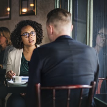 Two Men Sitting in Front of Brown Table Beside Glass Surface