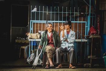 Two Men Sitting on Stool Painting