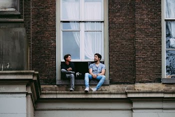 two men sitting on windowpane mantle