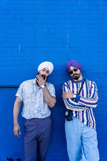 Two Men Standing and Leaning on Blue Wall