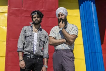 Two Men Standing Beside A Colorful Wall
