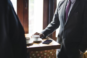 Two Men Standing Beside Table Near Wall