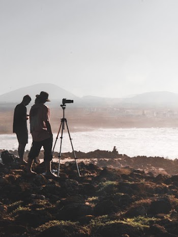 Two Men Standing on Rock Taking Photo Body of Water