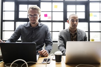 Two Men Using Laptop on the Table