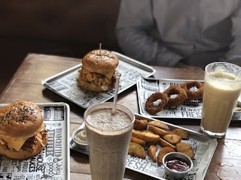 Two Milk Shakes, Burgers, Fried Onion Rings and Wedge Potatoes on the Table