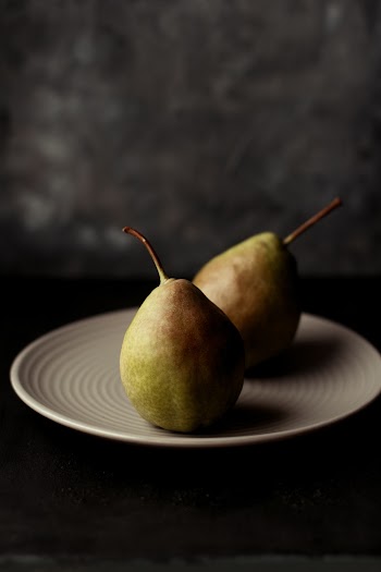 Two Oval Green Fruits on White Ceramic Plate