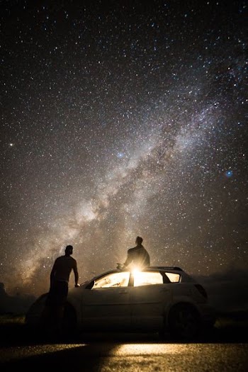 two people beside white car under galaxy