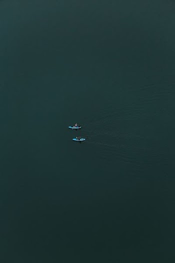 two people kayaking at calm body of water