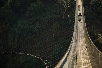 Two People Riding Motor Scooter and Another Person Walking on Bridge